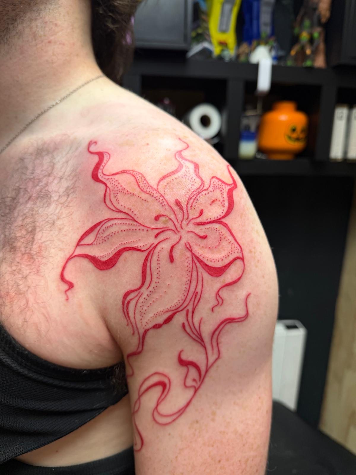 Red flowing botanical shoulder tattoo by Jodi Tattoos at West End Art Collective Galway